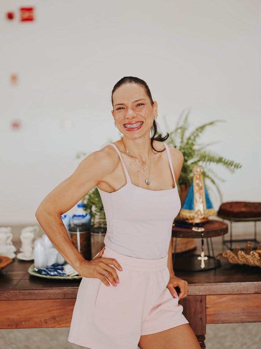 Monalysa Rodrigues sorrindo, de top e short rosa-claro, com a mão na cintura